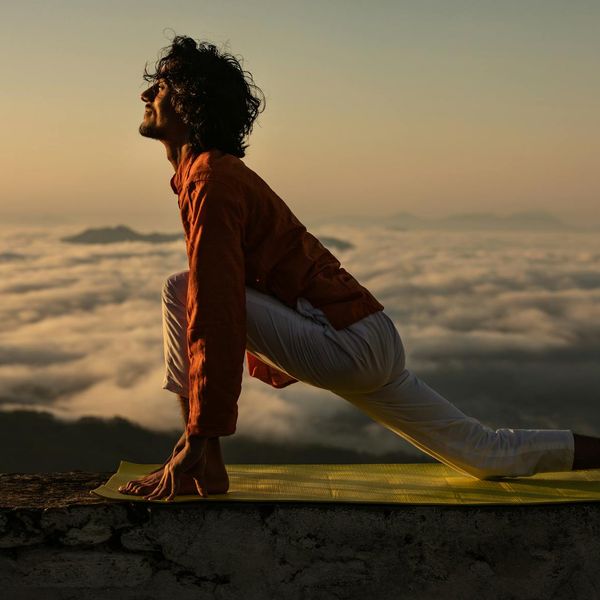 Silhouette of a man stretching against a sunrise, symbolizing balance and well-being.